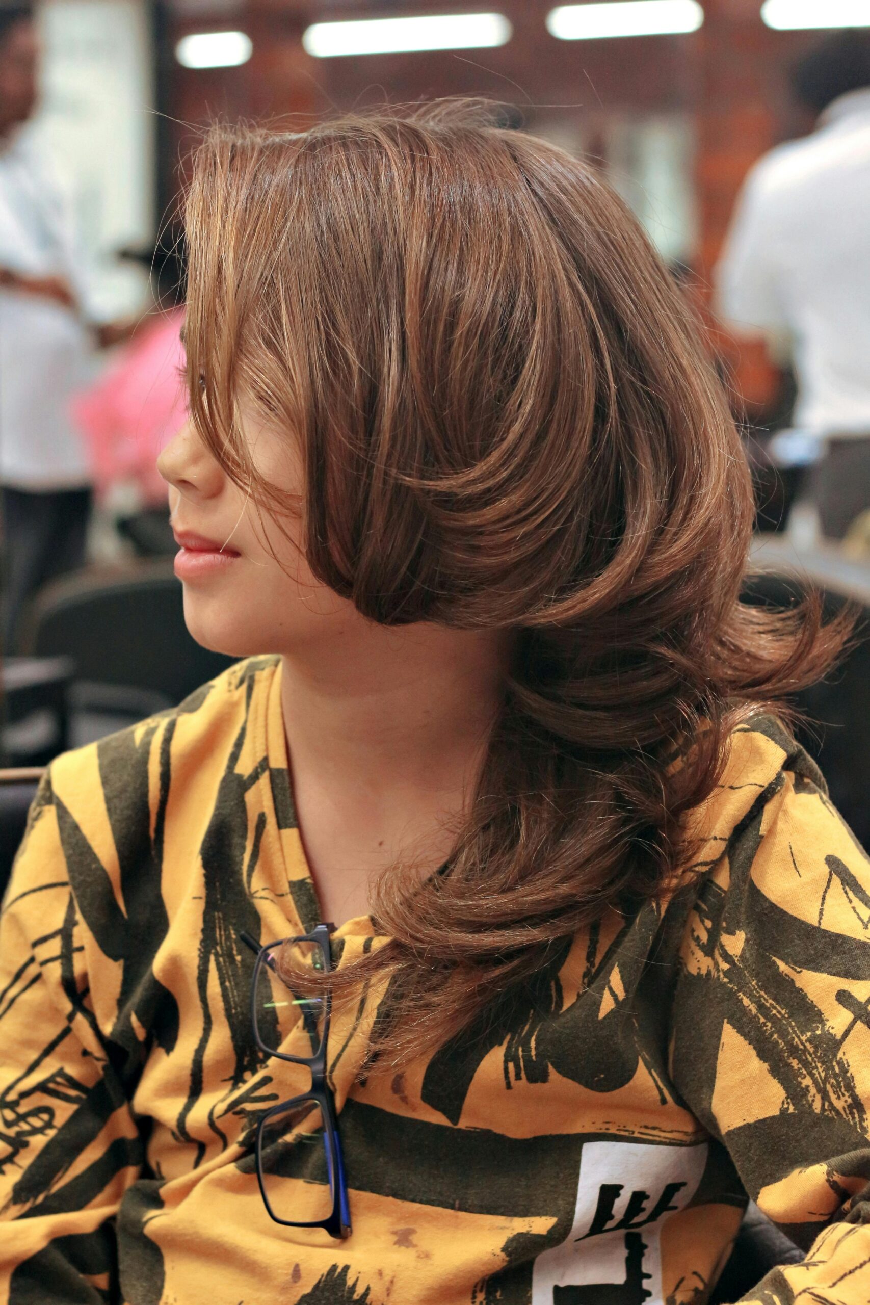 A woman with a stylish haircut sits in a modern salon, showcasing her beautifully styled hair.