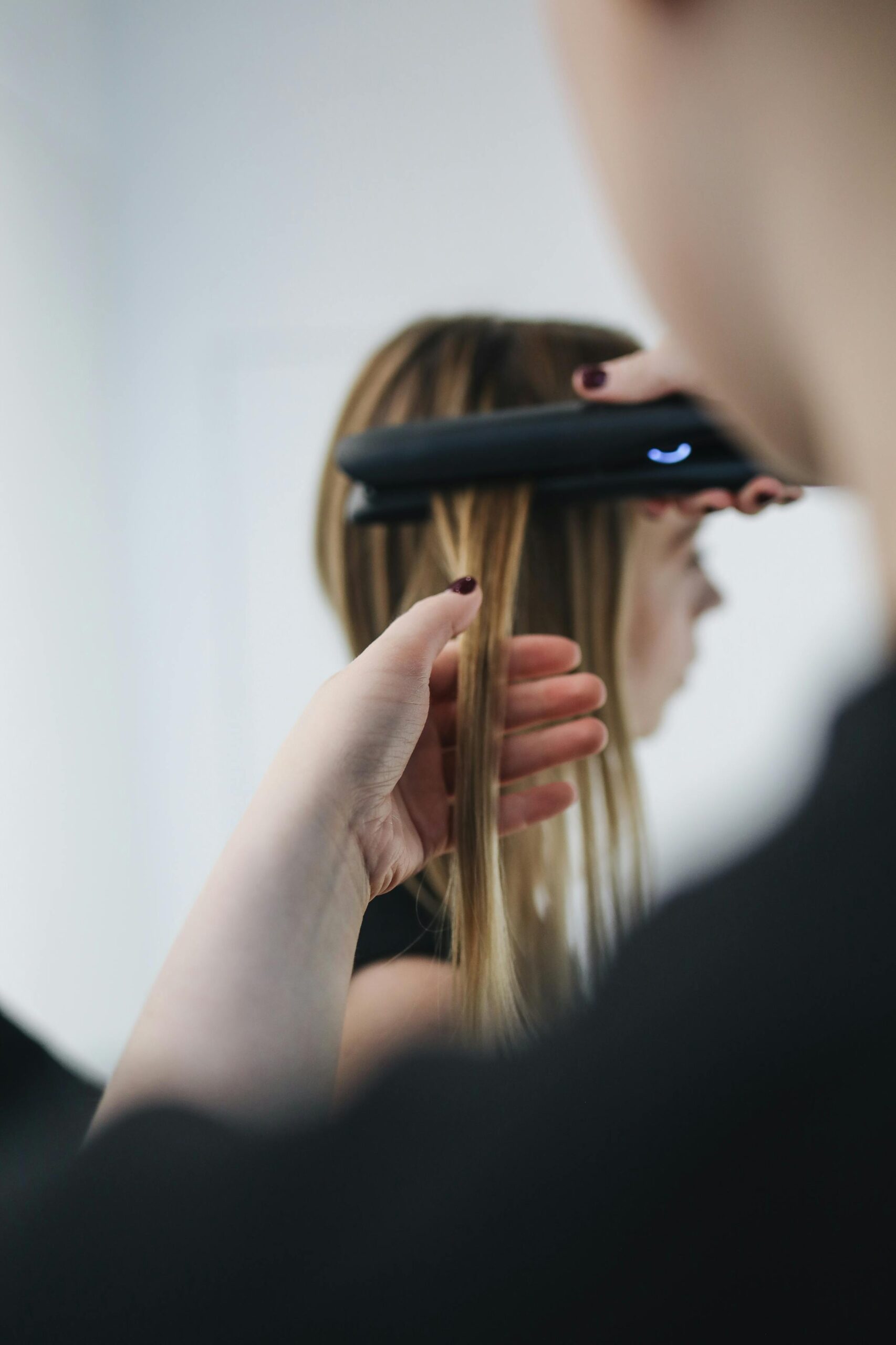 Close-up shot of a hairstylist straightening hair in a salon setting.